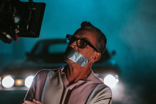 Actor in sunglasses in a car, lit in blue during the shoot