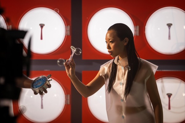 Actress in white in front of a red and white set on a commercial shoot