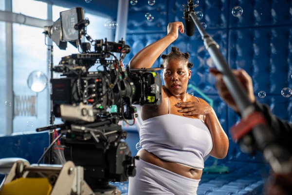 Camera operator filming an actress in a white dress up close