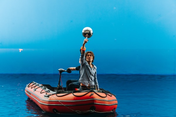 Actor in an inflatable boat against a blue sky on set