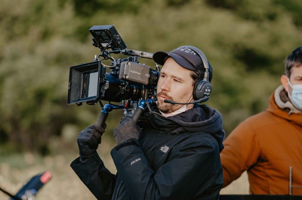 Camera operator with a cinema camera on his shoulder outdoors