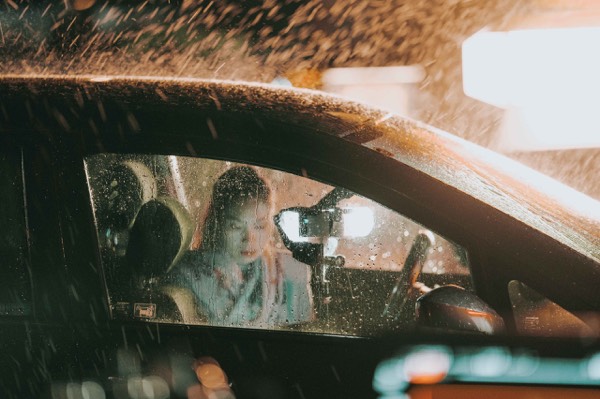 Actor in a car under rain machines on set