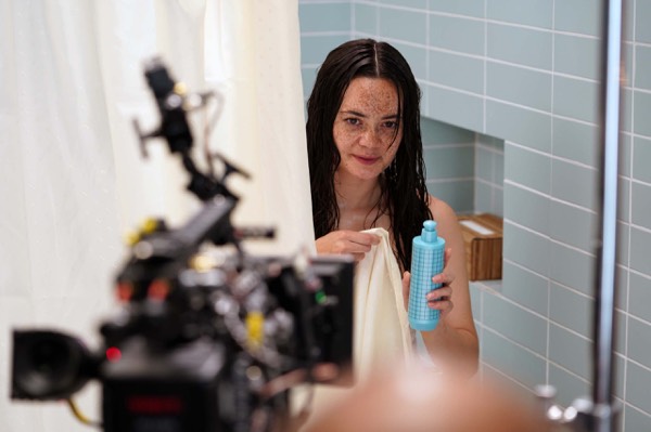 Camera filming an actress in a bathroom set in a studio