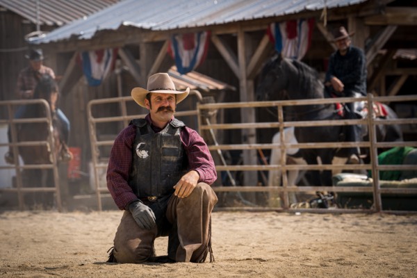 Actor kneeling in an arena on a western set