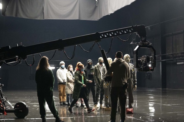 A large crew and cast in a dark sound stage