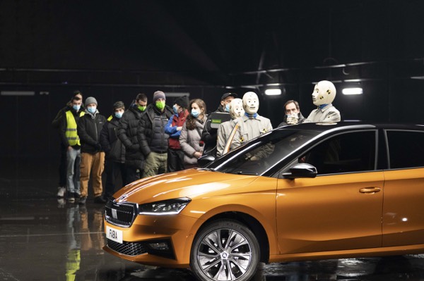 Crew and cast around an orange car on a commercial shoot