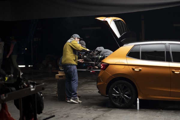 The crew preparing an orange car in a dark studio