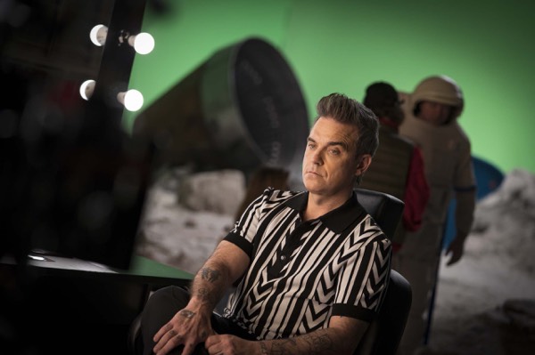 Performer in a striped shirt in front of a green screen