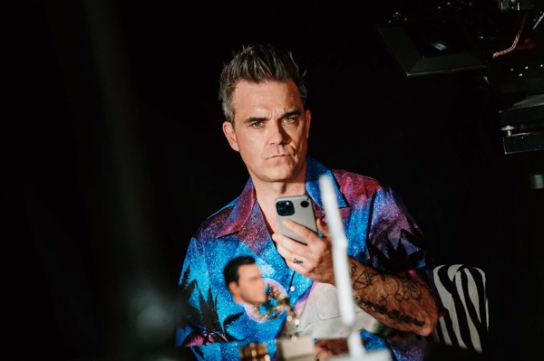 Performer in a patterned shirt in a dark studio
