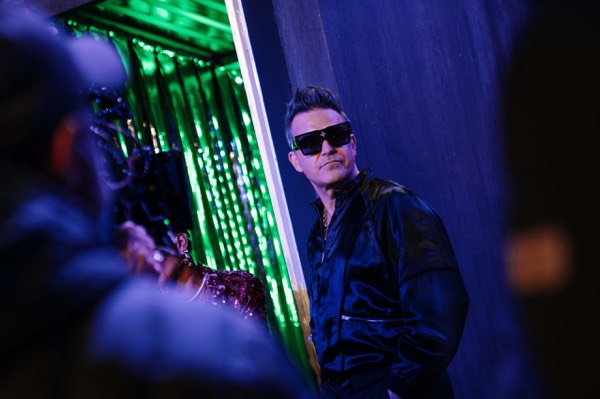 Performer in green and blue light on set