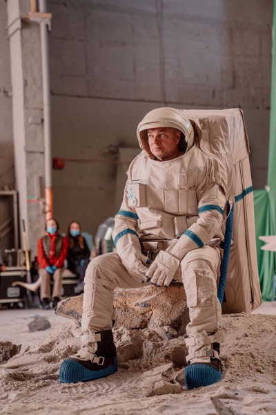 Actor in an astronaut suit sitting in a studio