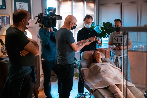 Crew with camera and lights around a scene in a studio